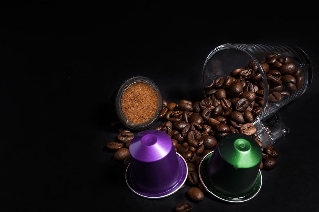 Indonesso purple and green coffee capsule surrounded by aromatic coffee beans