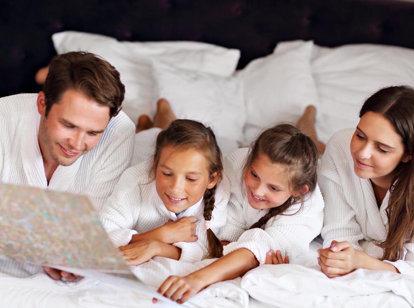 family-guy-is-showing-the-hotel-map-to-his-family-on-the-hotel-white-bed