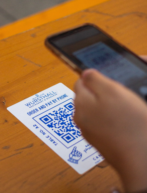 A male customer making a payment at a restaurant using a QR code on his phone