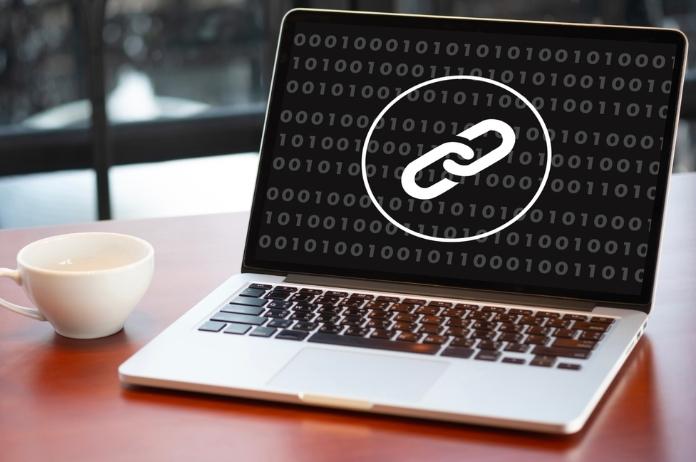 A white MacBook displaying logo of chain link in black background