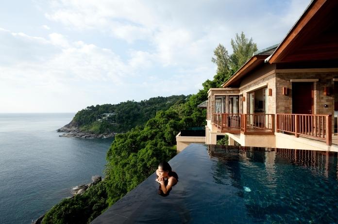 Female guest enjoying hotel infinity pool surrounded by trees and ocean view