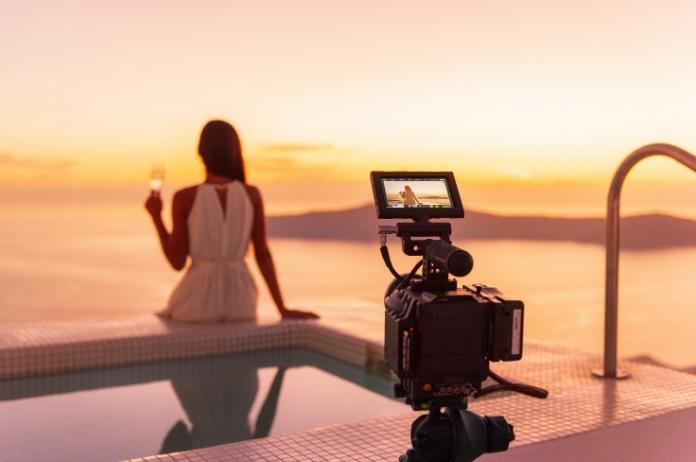 Female guest being recorded while enjoying a glass of wine on the hotel pool during sunset
