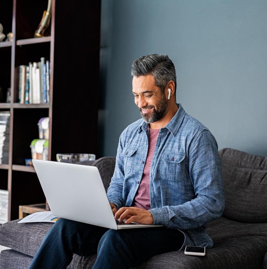 adult man with casual clothes sit on the grey sofa and laptop on his knee and put a smile face as excellent user experience