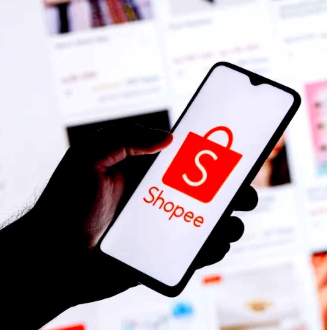 man finger hold a smartphone that displays shopee optimization advertising and shopee website as a background behind it