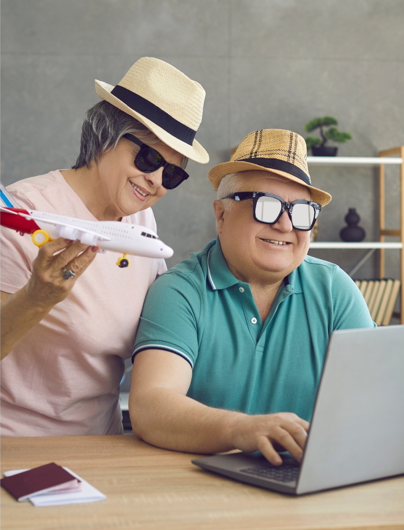 one-old-woman-with-straw-hat-and-black-glasses-hold-the-plane-toy-beside-her-husband-that-wear-a-straw-hat-and-glasses-look-at-the-laptop-to-search-about-online-booking-system-for-travel