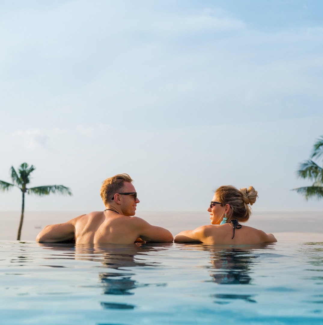 two couples in the hotel pool look at to each other with an infinity landscape as the background