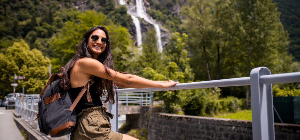A woman taking a picture on a bridge with waterfall view